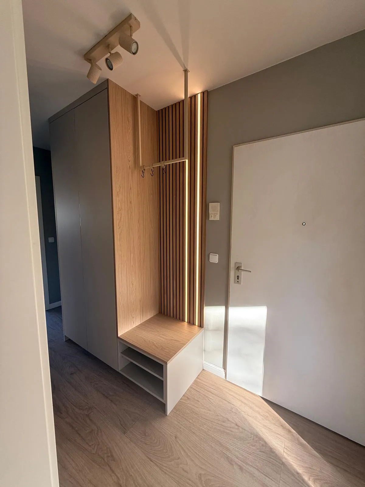 Eine Garderobe verbindet hohe Schrankfronten mit einer Sitzbank und einer Rückwand in Lamellenoptik.