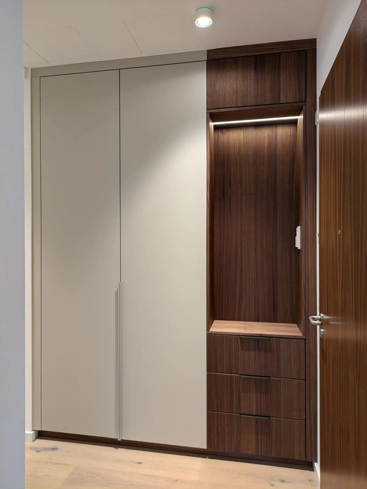 Taupefarbene Garderobe mit beleuchteter Sitznische und dunkler Holzmaserung