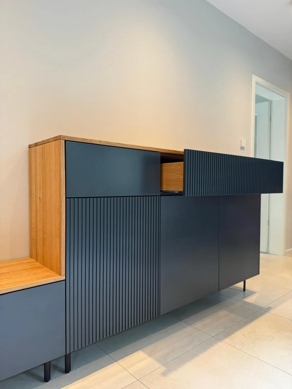 Ein dunkelblaues Sideboard mit gerillten Fronten und einem geöffneten Schubkasten.